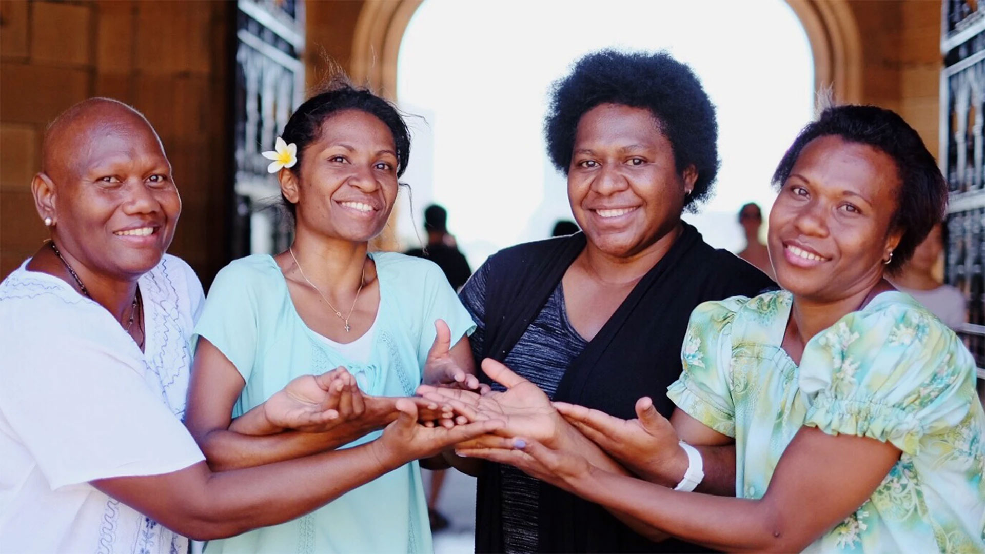 4 people holding hands and smiling at the camera