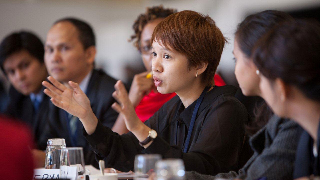 A woman leads a conversation at a table with people sitting alongside her