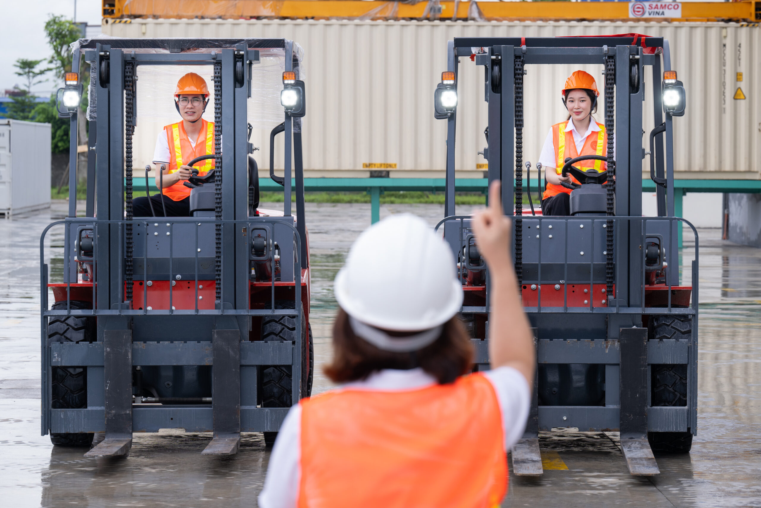 People wearing high-vis vests. One is directing two forklift drivers.
