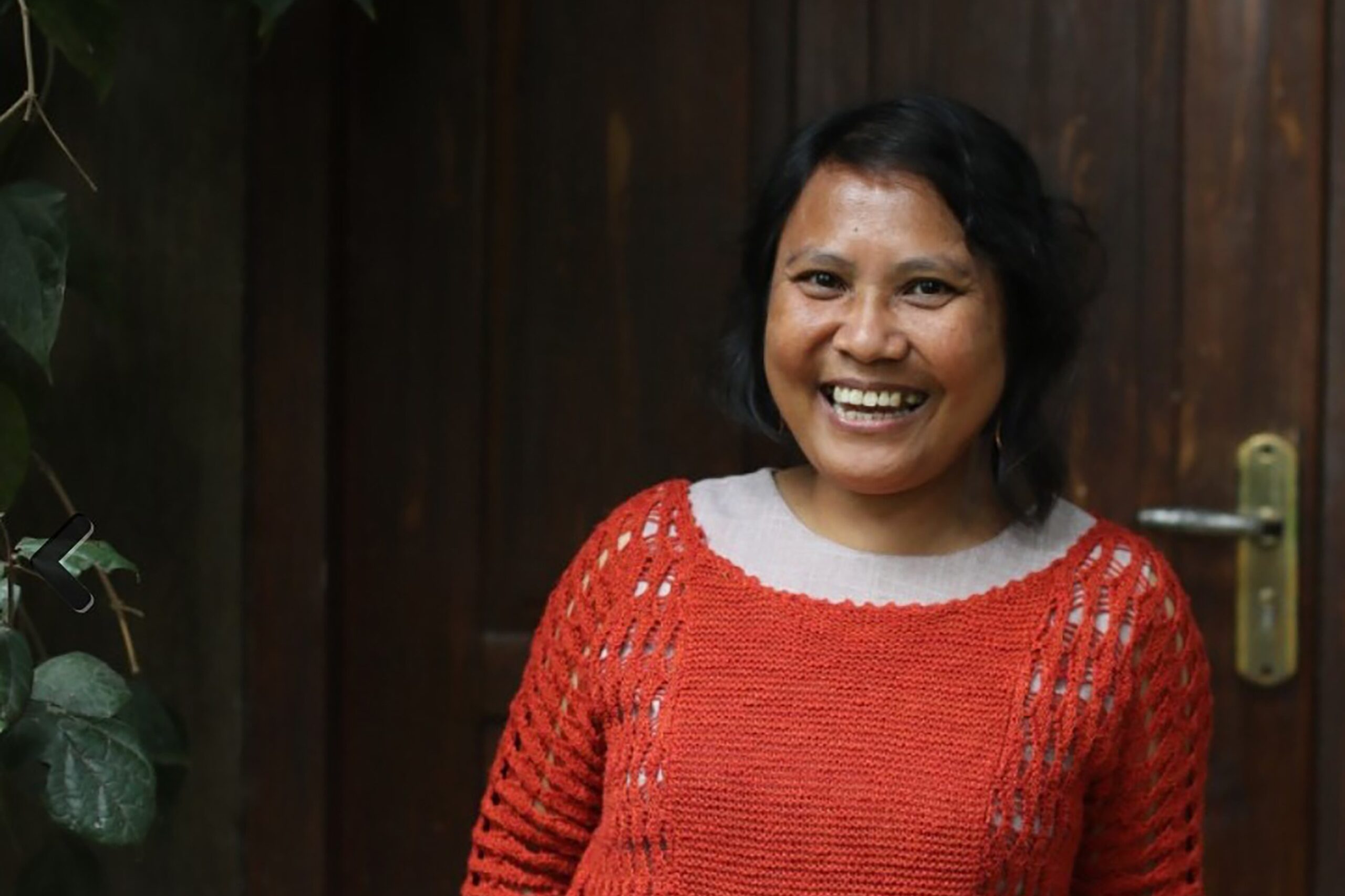 Nerlian Gogali standing in front of a wooden door.