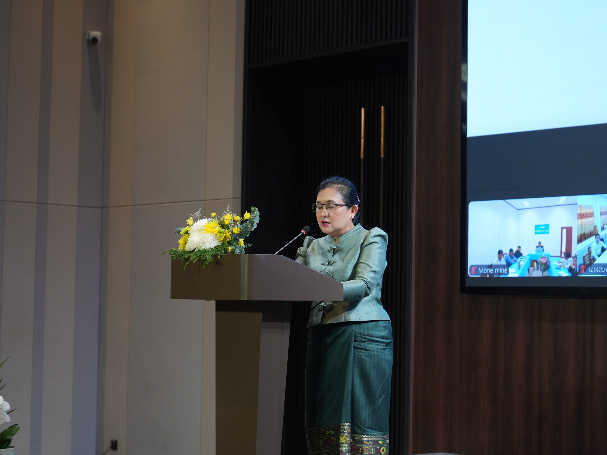 Dr. Daravone Kittiphanh stanbding infront of a microphone delivering a speech